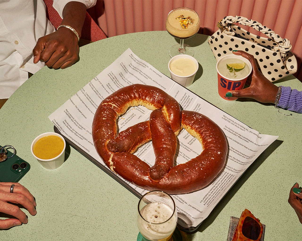 Friends enjoy a giant pretzel with dipping sauces