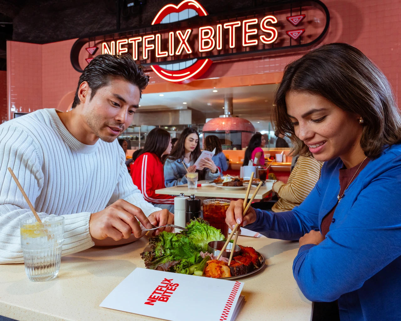 A couple has date night at Netflix Bites and shares a salad. 