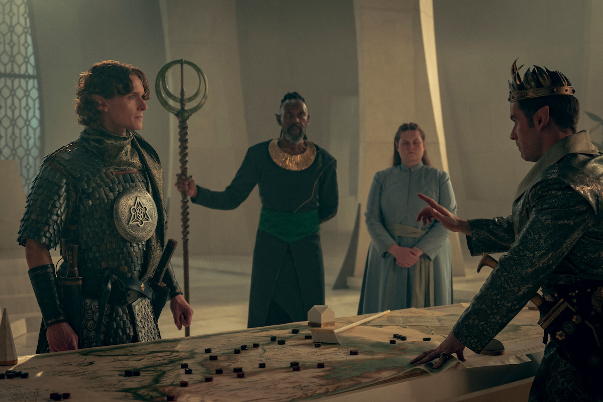 Character stand around a table discussing tactics.