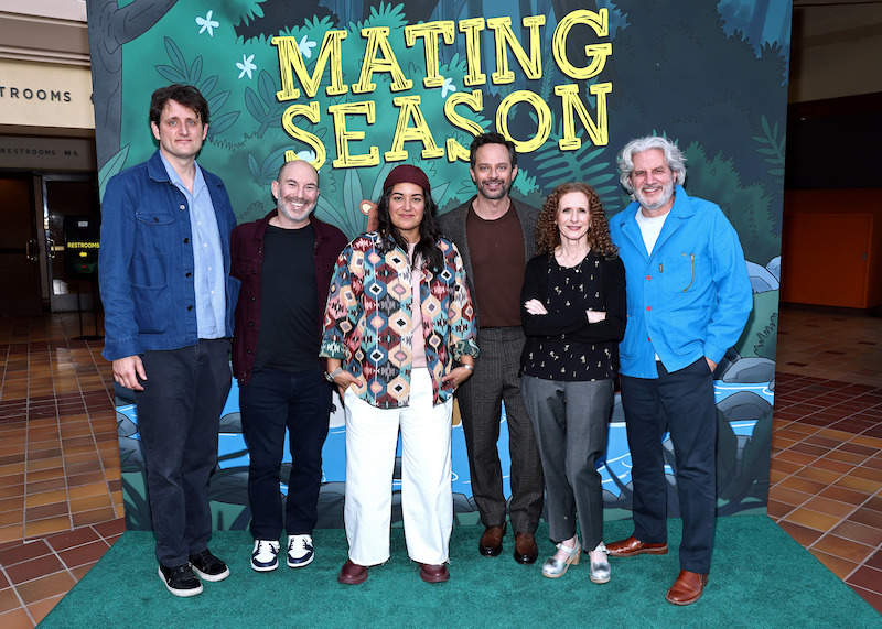 A group of people pose in front of a step and repeat that says Mating Season.