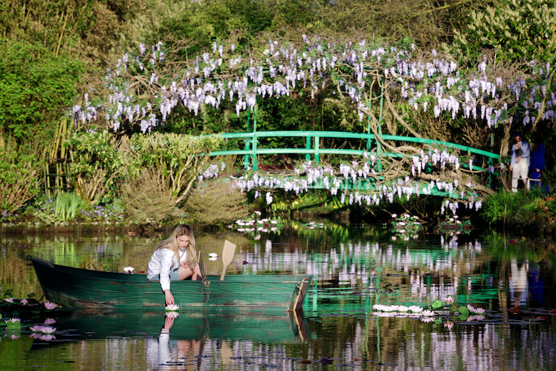 Camille Razat, como Camille, rema um barco em um lago cheio de flores na temporada 4 de ‘Emily em Paris’