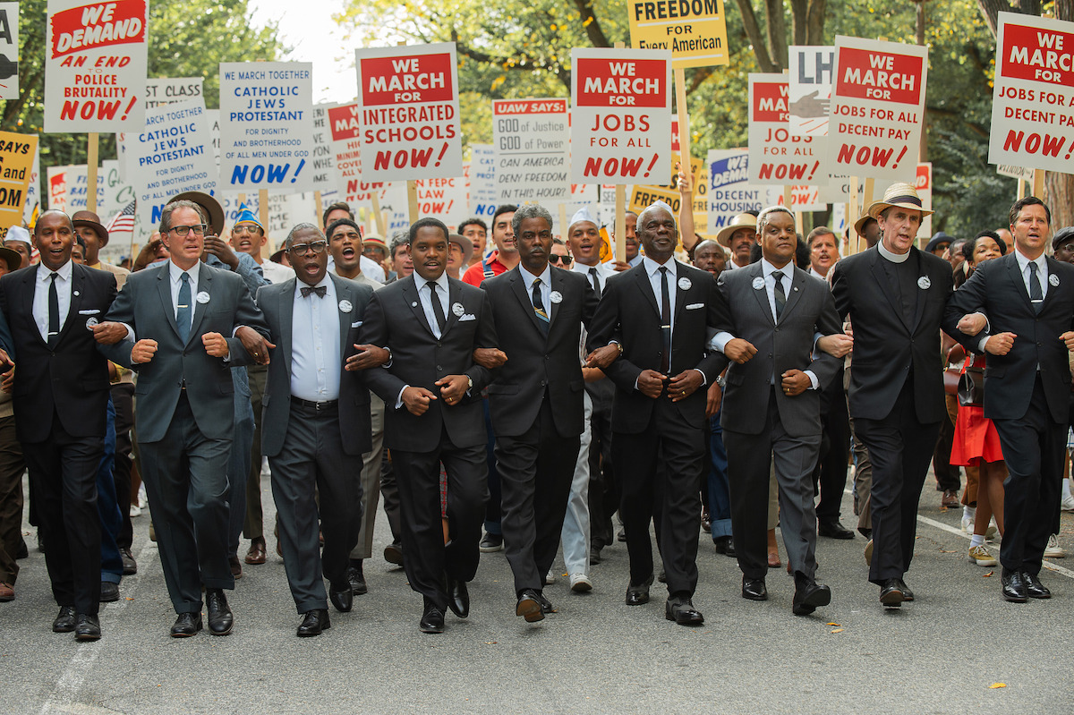 Aml Ameen as Martin Luther King Jr. and Chris Rock as Roy Wilkins link arms during the March on Washington in a still from ‘Rustin.’