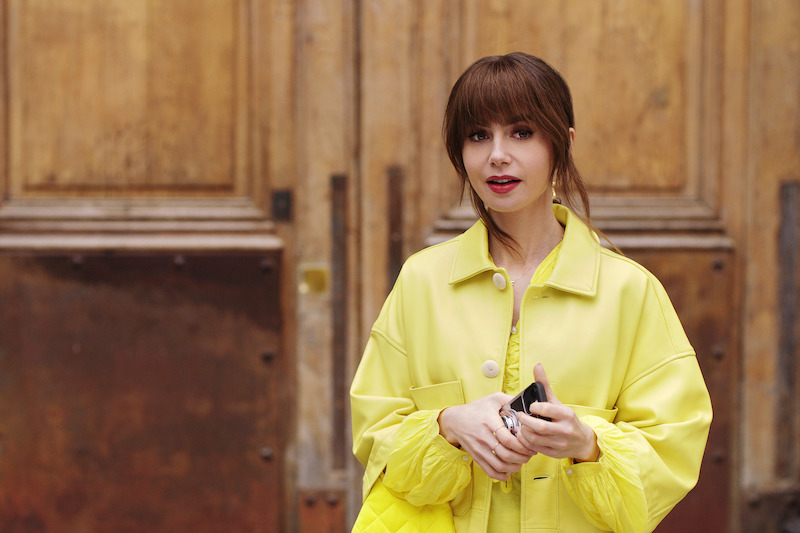 Lily Collins, como Emily, veste um casaco amarelo brilhante na temporada 4 de ‘Emily em Paris’