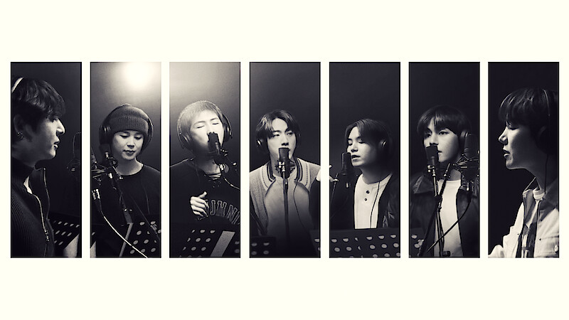 Seven people in a recording studio, each standing at a microphone with music stands, singing or speaking, black and white, portrait orientation, individual spotlight on each person, professional, creative environment.