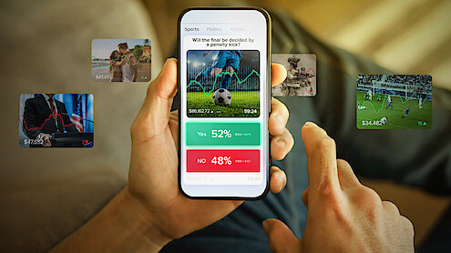 Person holding a smartphone displaying a sports betting app with options and statistics, surrounded by floating images of various sports scenes, sitting on a couch in a relaxed indoor setting.