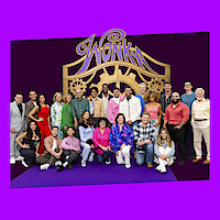 Large group of people posing together on a purple carpet in front of a golden "Wonka" gate backdrop, dressed in colorful outfits, with a purple background, suggesting a themed event or celebration setting.