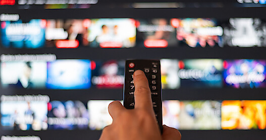 Remote pointing at television with streaming service display.